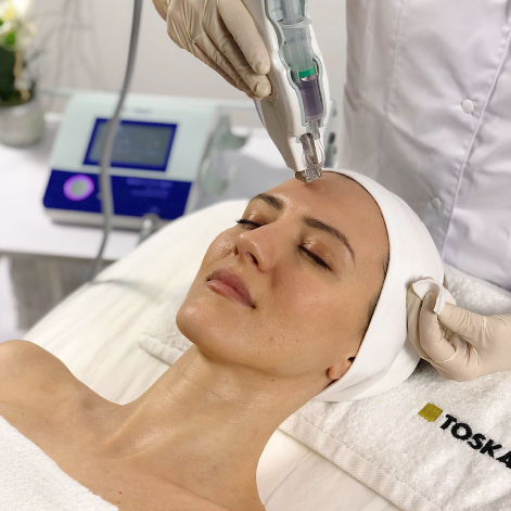 Toskani MesojectGun treatment being used on the face in a professional medspa setting